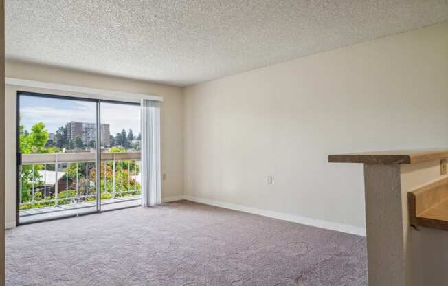 an empty living room with a balcony and sliding glass doors