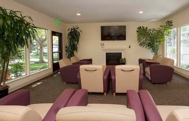 A living room with purple and white furniture and a flat screen TV mounted on the wall.