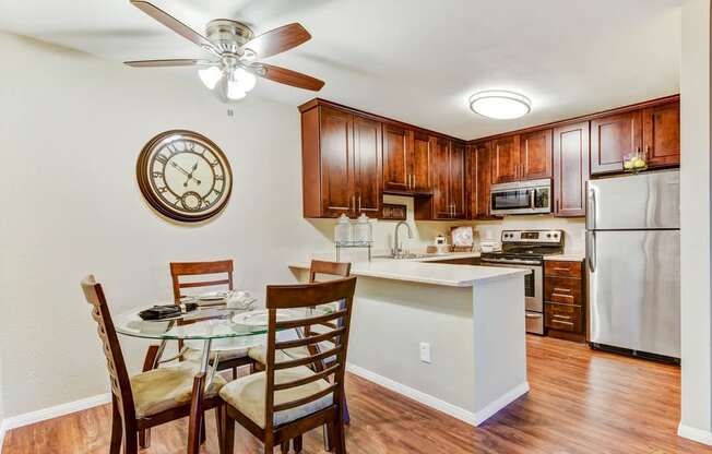 A kitchen with a table and chairs and a clock on the wall.