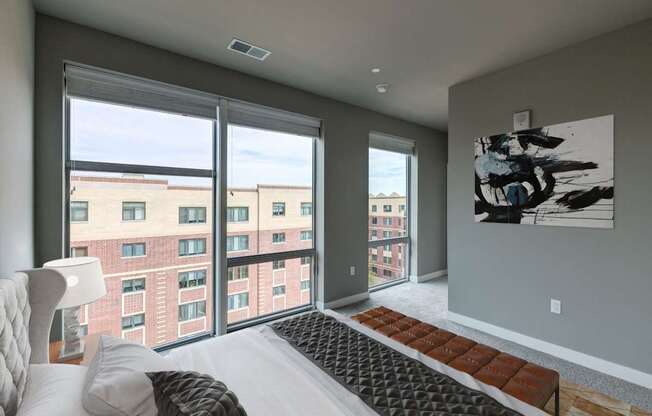 A modern bedroom with a large bed and a view of the city.