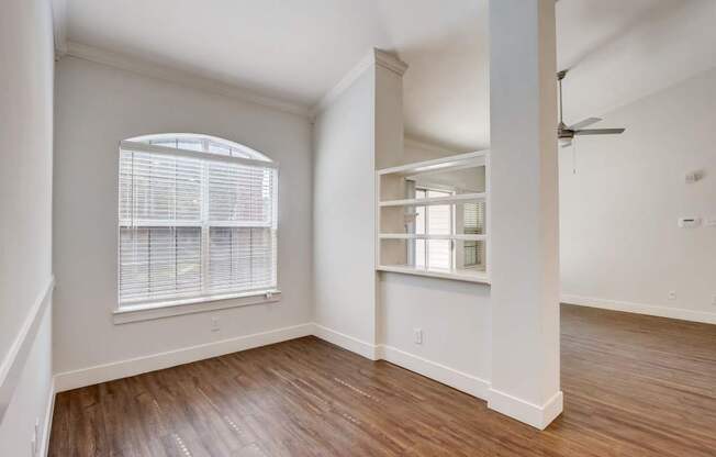 an empty living room with a large window and wooden floors