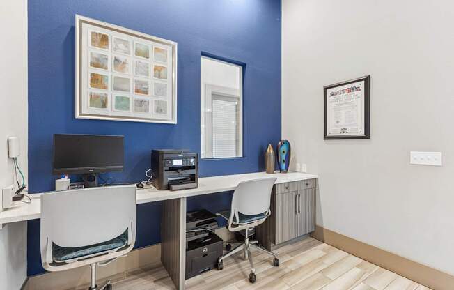A blue wall with a white chair and a computer on a desk.