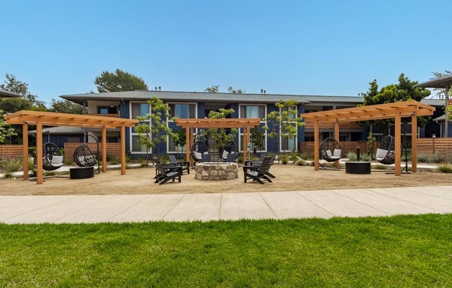 a patio with benches and umbrellas in front of a house