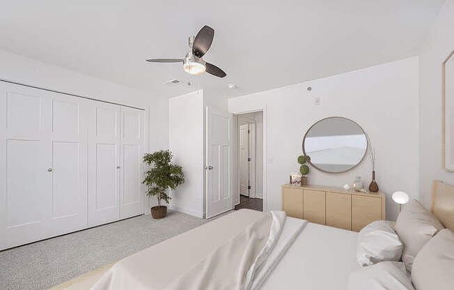 A bedroom with a bed, dresser, mirror, and a ceiling fan at Copper Creek Apartment Homes, Maize, Kansas
