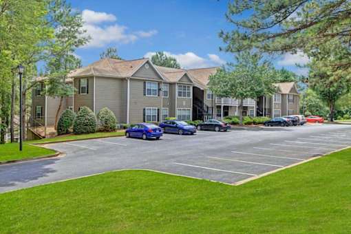 A parking lot in front of a building with cars parked.
