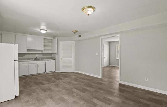 the living room and kitchen of an apartment with white cabinets and white appliances