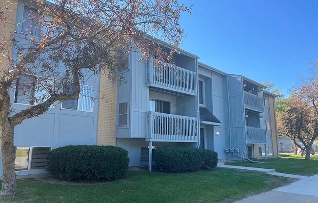 an apartment building with a sidewalk and a tree in front of it