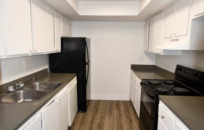 an empty kitchen with white cabinets and a black stove and refrigerator