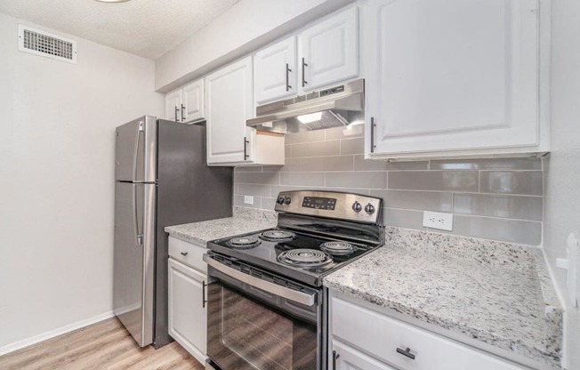 a kitchen with white cabinets and a stainless steel refrigerator