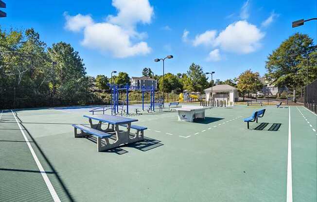 A tennis court with a blue bench and a white fence.