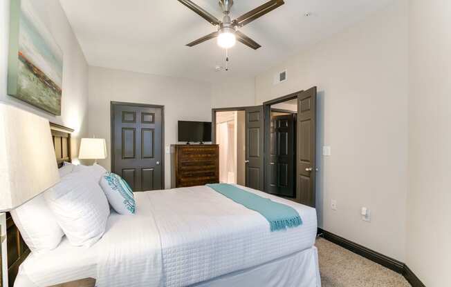 a bedroom with a large white bed and a ceiling fan