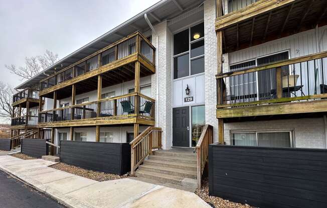 the exterior of an apartment building with stairs and a black fence