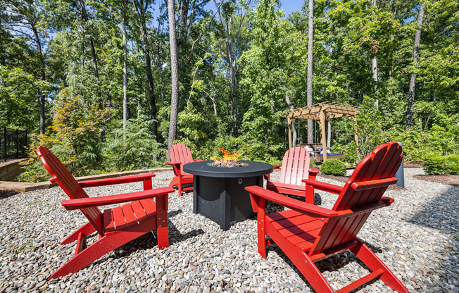 a group of red chairs sitting around a firepit