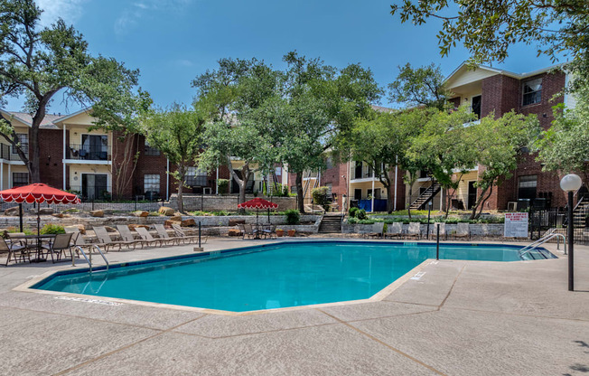 A swimming pool surrounded by trees and chairs.