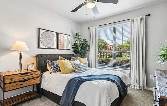 A bedroom with a bed, nightstand, and a ceiling fan.