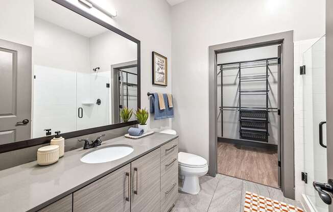A bathroom with a toilet, sink, and mirror.