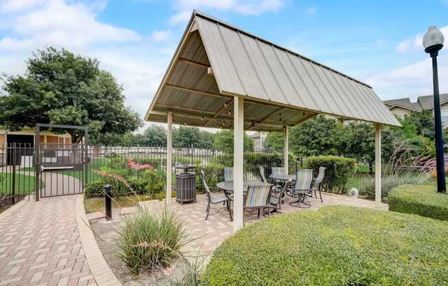 a pavilion with a table and chairs on a brick patio