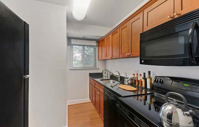 A kitchen with black appliances and wooden cabinets.