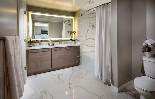 A bathroom with a marble floor and a large mirror above the sink.