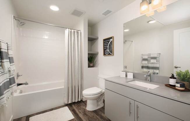 A white bathroom with a toilet, sink, and shower.