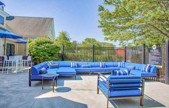 Outdoor patio with blue couches and umbrellas at Windsor Ridge at Westborough, Westborough, MA