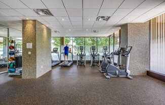 A gym with a variety of exercise equipment including treadmills, stationary bikes, and elliptical machines.