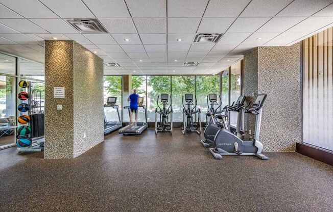 A gym with a variety of exercise equipment including treadmills, stationary bikes, and elliptical machines.