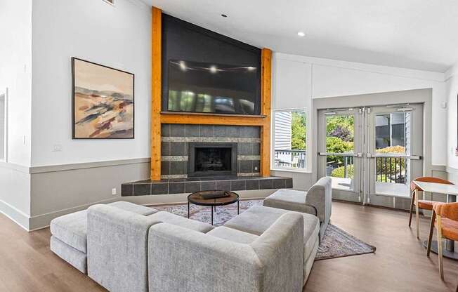 A living room with a grey couch and a fireplace.