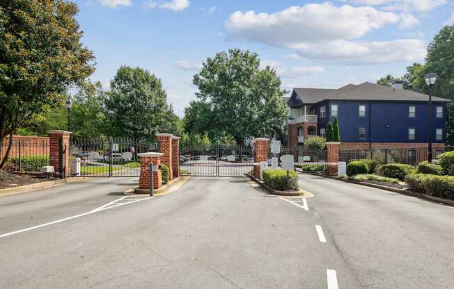 A blue building is behind a gate and a brick wall.