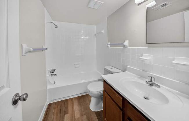 A white bathroom with a toilet, sink, and shower.