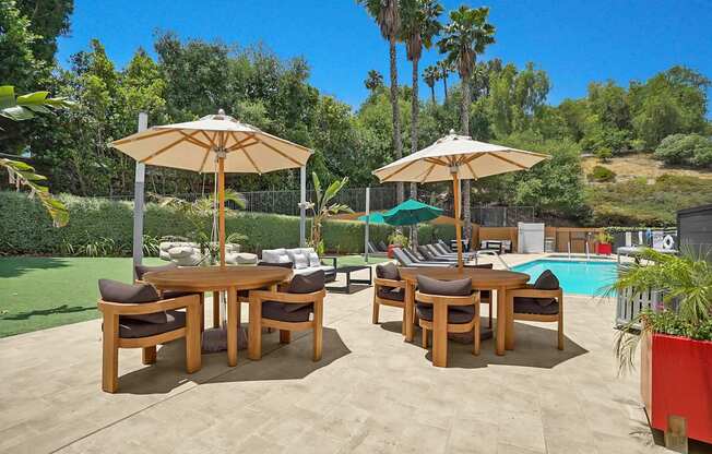 A patio with a table and chairs and umbrellas.
