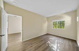 a bedroom with hardwood floors and beige walls at The Village Apartments, Van Nuys California