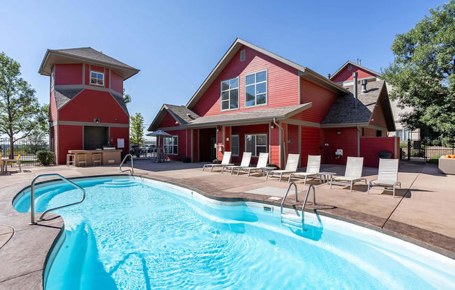 the pool is in front of a red house with a swimming pool at Stetson Meadows Apartments, Colorado Springs