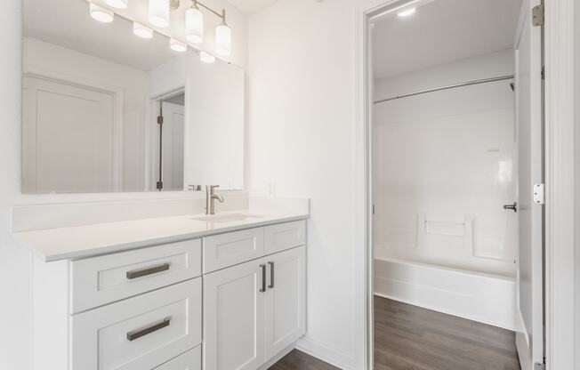 a white bathroom with a large mirror and a sink and a shower