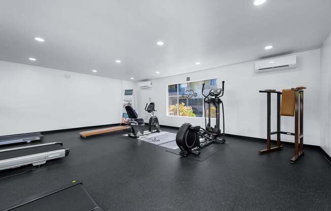 A gym with a variety of equipment including a treadmill, weights, and a bench press.