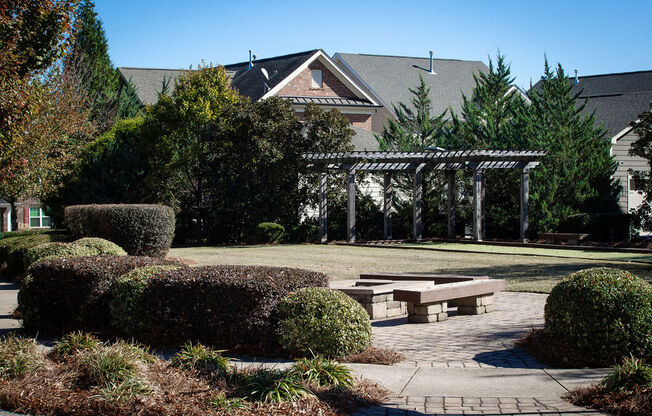 a courtyard with benches and a pergola in front of a house