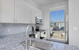 Kitchen with white cabinets, stainless steel appliances and granite countertops, window with skyline view