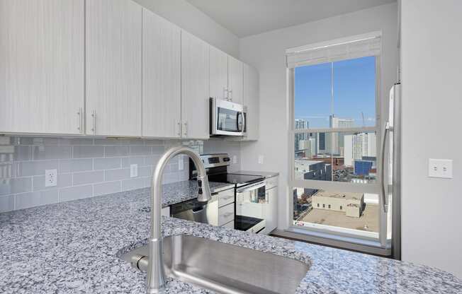 Kitchen with white cabinets, stainless steel appliances and granite countertops, window with skyline view