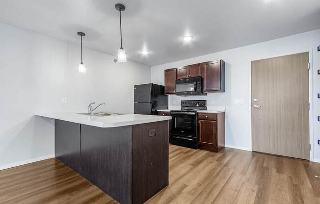 A kitchen with a white counter top and wooden floors.