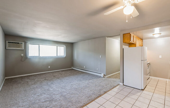 an empty living room with a white refrigerator