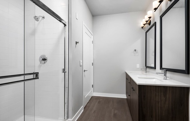 A bathroom with a walk-in shower, double sinks, and a large mirror.