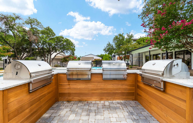 two bbq grills in the backyard of a home with a pool in the background