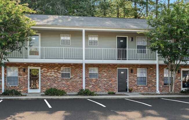 a red brick building with a balcony and a parking lot