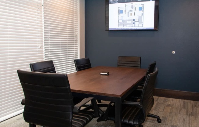 A conference room with a large screen and chairs.
