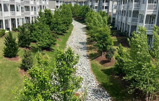 an aerial view of an apartment complex with a gravel path and trees