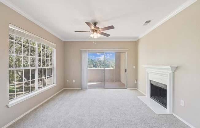 an empty living room with a fireplace and a ceiling fan