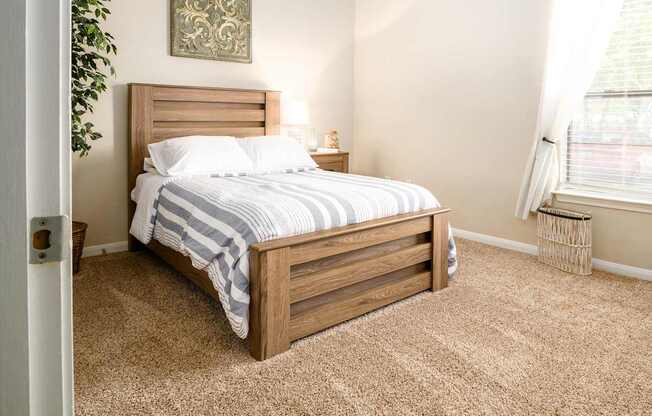 A bedroom with a bed, nightstand, and a plant.