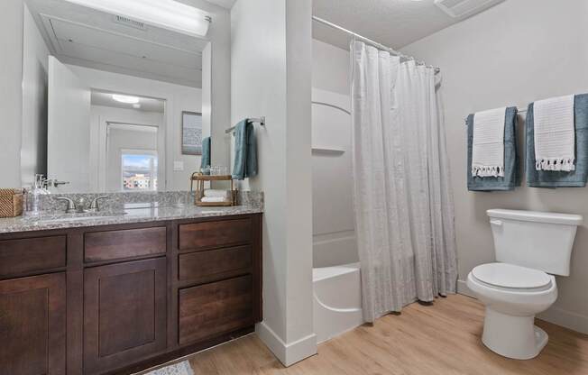 A white toilet sits next to a shower curtain in a bathroom.