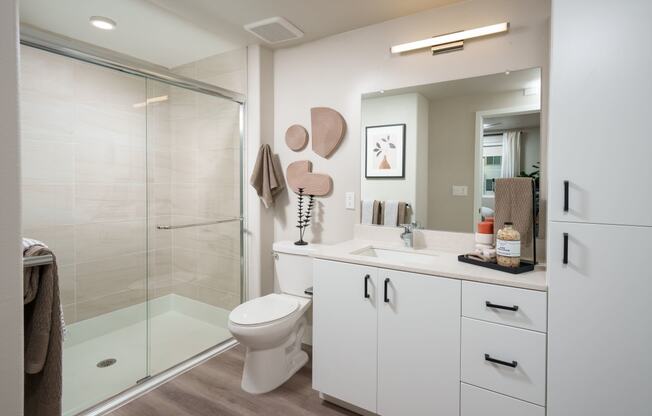 Dog-Friendly Garden-Style Apartments in Rancho Cordova, CA - Aurora - Bathroom with Vinyl Plank Flooring, Glass-Framed Walk-In Shower,  Soft-Close Cabinets, and Vanity with Quartz Countertop.