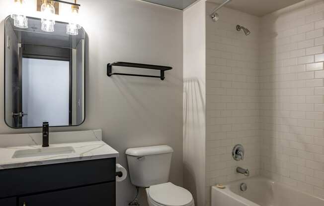 a bathroom with a toilet sink and mirror and a bath tub